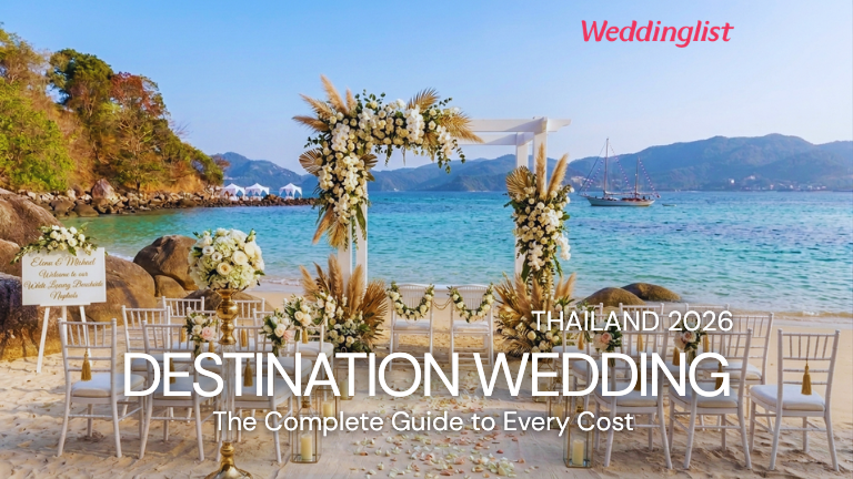 A beautiful beachfront ceremony setup for a romantic destination wedding in Thailand, featuring a white floral arch, elegant guest chairs on the sand, and a scenic blue ocean backdrop.